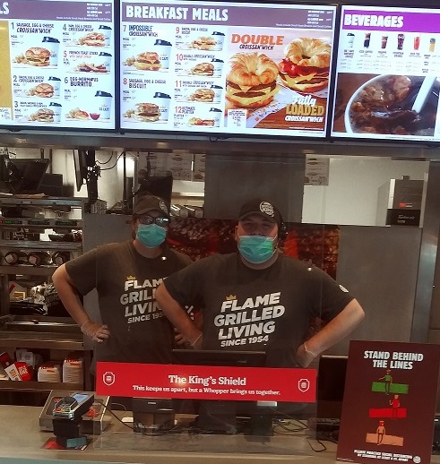 Burger King employees behind a protective plastic shield.
