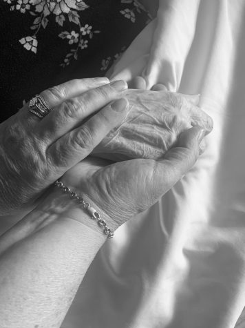 A daughter cradles the hand of her dying mother.