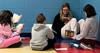 LHS Teaching Academy and Childcare student Bree Hilyard reads with elementary students.
